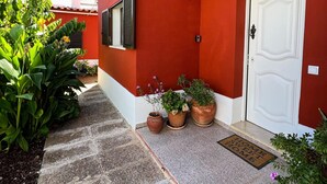 A red building with a white door, potted plants, and a stone pathway. - Sunshine Villa (Faro)