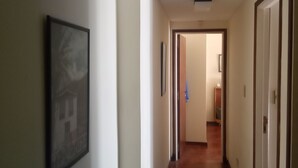 Ein Flur mit Holzboden, weißen Wänden und einem gerahmten Bild auf der linken Seite.