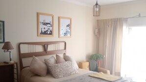 Ein Schlafzimmer mit einem Bett, einem Nachttisch, einer Lampe, einer Pendelleuchte und zwei gerahmten Bildern an der Wand.