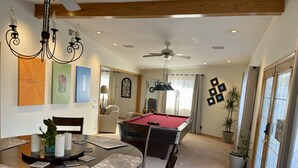 A spacious living room with a pool table, a dining area with a round table and chairs, and a ceiling fan. - Cheerful Single Story 3-bedroom home w pool table (Santa Clarita)