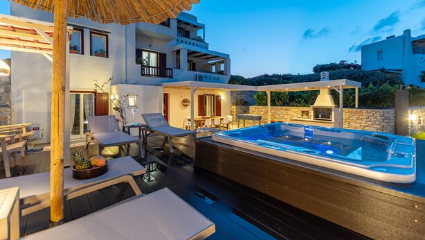 A modern outdoor pool area with lounge chairs and a hot tub, surrounded by a wooden deck and a stone wall. - Aurora Villa II with private Jacuzzi - Naxos (Agios Prokopios)