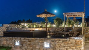 An outdoor patio with stone walls, a pergola, and lounge chairs. - Aurora Villa II with private Jacuzzi - Naxos (Agios Prokopios)
