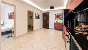 A modern kitchen with black countertops, a refrigerator, and a dining area with a table and chairs. - Aurora Villa II with private Jacuzzi - Naxos (Agios Prokopios)