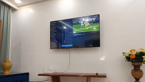 A flat-screen TV mounted on a wall displaying a sports channel menu and a soccer match. - Luxury Family House with Garden View Casablanca (Dar-el-Beida)
