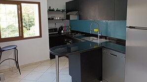 A modern kitchen with a black countertop, stainless steel appliances, and a window with a view of greenery. - Luxury Family House with Garden View Casablanca (Dar-el-Beida)