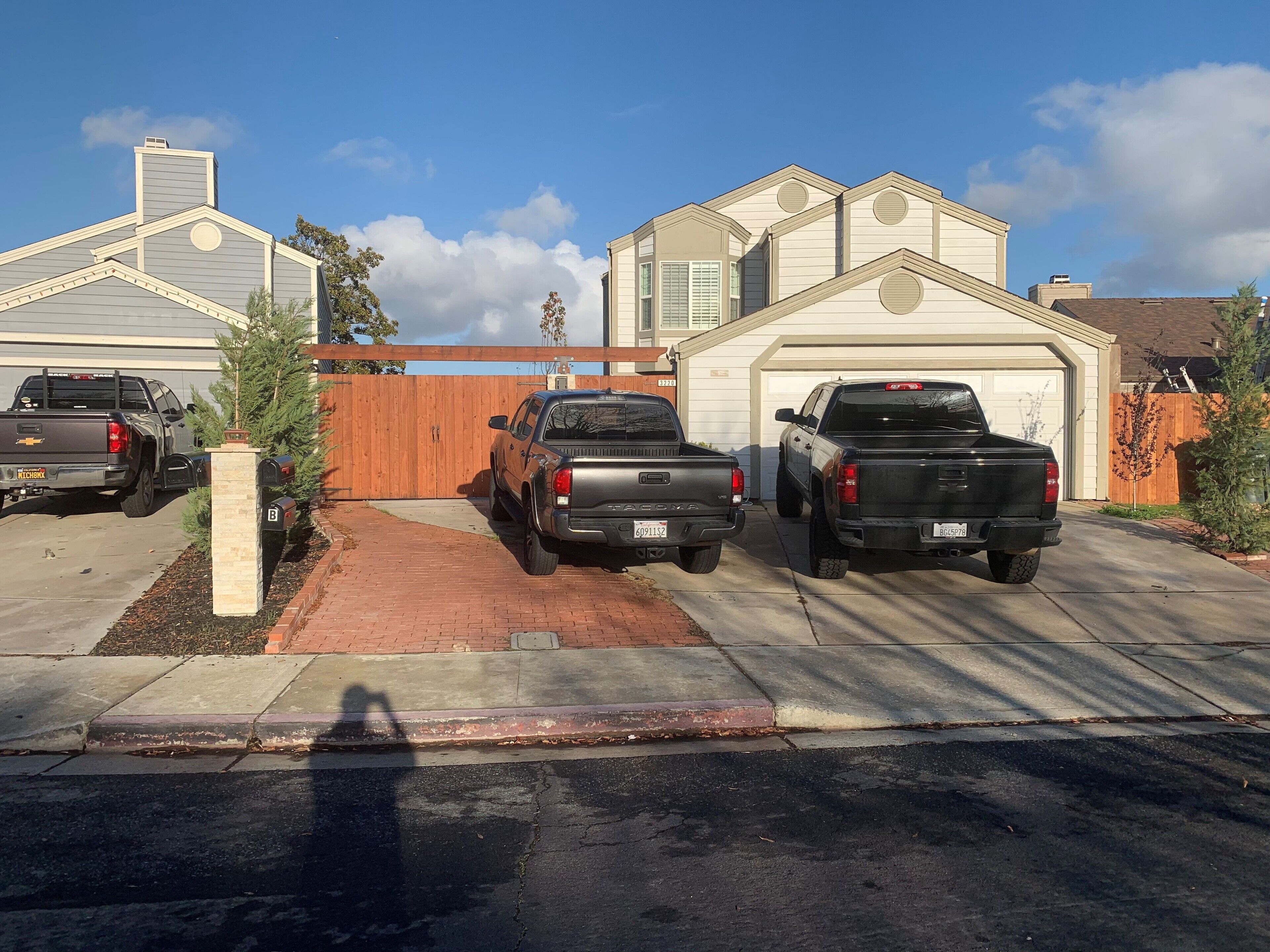 Un camino de acceso residencial con tres camionetas estacionadas.