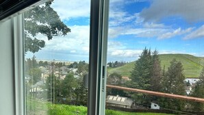 A view through a window of a rural landscape with a hill, trees, and a distant building. - Beautiful place and view to rest and clear your mind.#1 (Antioch)