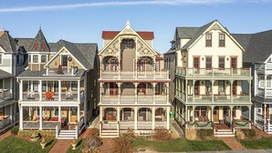 A multi-story building with a central balcony, multiple windows, and a decorative front porch. - Four Oceanview Balconies overlooking the beach!  (Neptune Township)