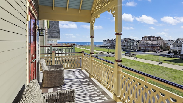 A balcony with wicker furniture, a view of the beach, and residential buildings in the background. - Four Oceanview Balconies overlooking the beach!  (Neptune Township)