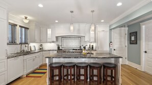 A modern kitchen with white cabinetry, a large island with bar stools, a stainless steel range, and a herringbone backsplash. - Four Oceanview Balconies overlooking the beach!  (Neptune Township)
