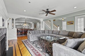 A spacious living room with a sectional sofa, a glass coffee table, and a patterned rug.