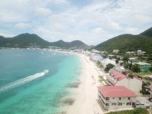 Un pueblo costero con una playa, edificios y montañas al fondo.