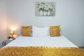 Ein Hotelzimmer mit einem Bett, zwei Zierkissen, einer Nachttischlampe und einem Bild an der Wand.