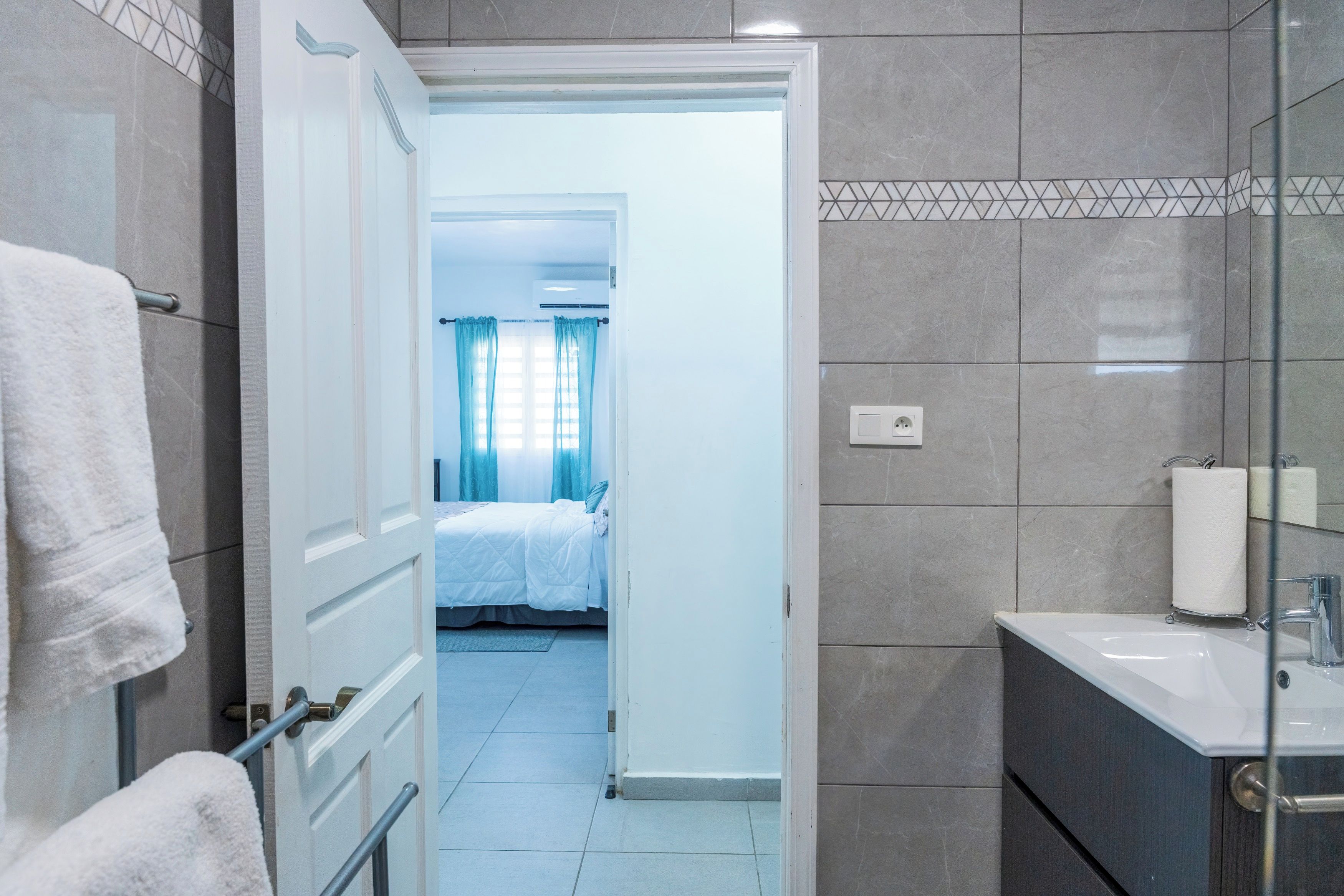Casa de banho de hotel com lavatório, espelho e porta-toalhas.