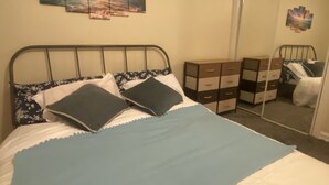Een slaapkamer met een bed, een dressoir en een spiegel.
