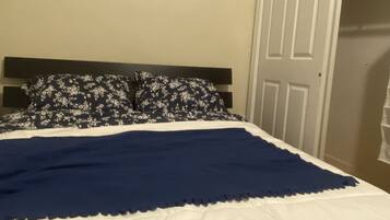 A bedroom with a bed, a nightstand, a wardrobe, and a painting on the wall.
