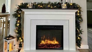 Ein modernes Wohnzimmer mit Kamin, einem Wand-Fernseher und festlicher Weihnachtsdeko.