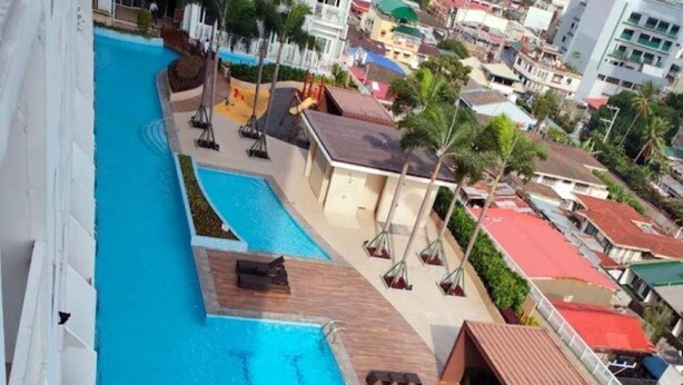 Una piscina sul tetto con acqua cristallina, lettini prendisole e vista sugli edifici circostanti.