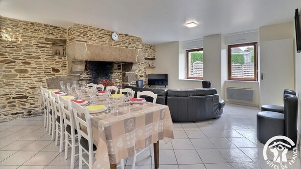 A dining area with a stone wall, a fireplace, a sofa, and a TV.