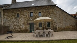 A stone building with a covered outdoor seating area and a table with chairs.