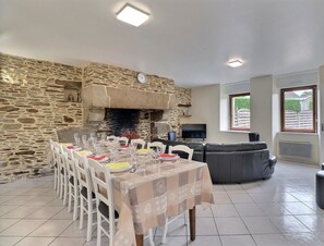 Ein Essbereich mit Steinwand, Kamin, einer Couch und einem Fernseher.