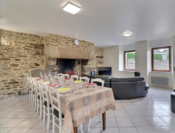 A dining area with a stone wall, a fireplace, a sofa, and a TV.