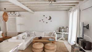 Een moderne woonkamer met een witte bank, een houten salontafel en een aan de muur bevestigde televisie.
