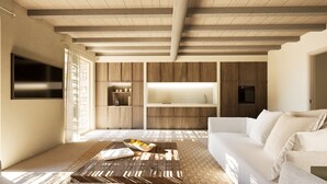 Een moderne woonkamer met een witte bank, een houten salontafel met een boek en een schaal fruit, en ingebouwde houten kasten.