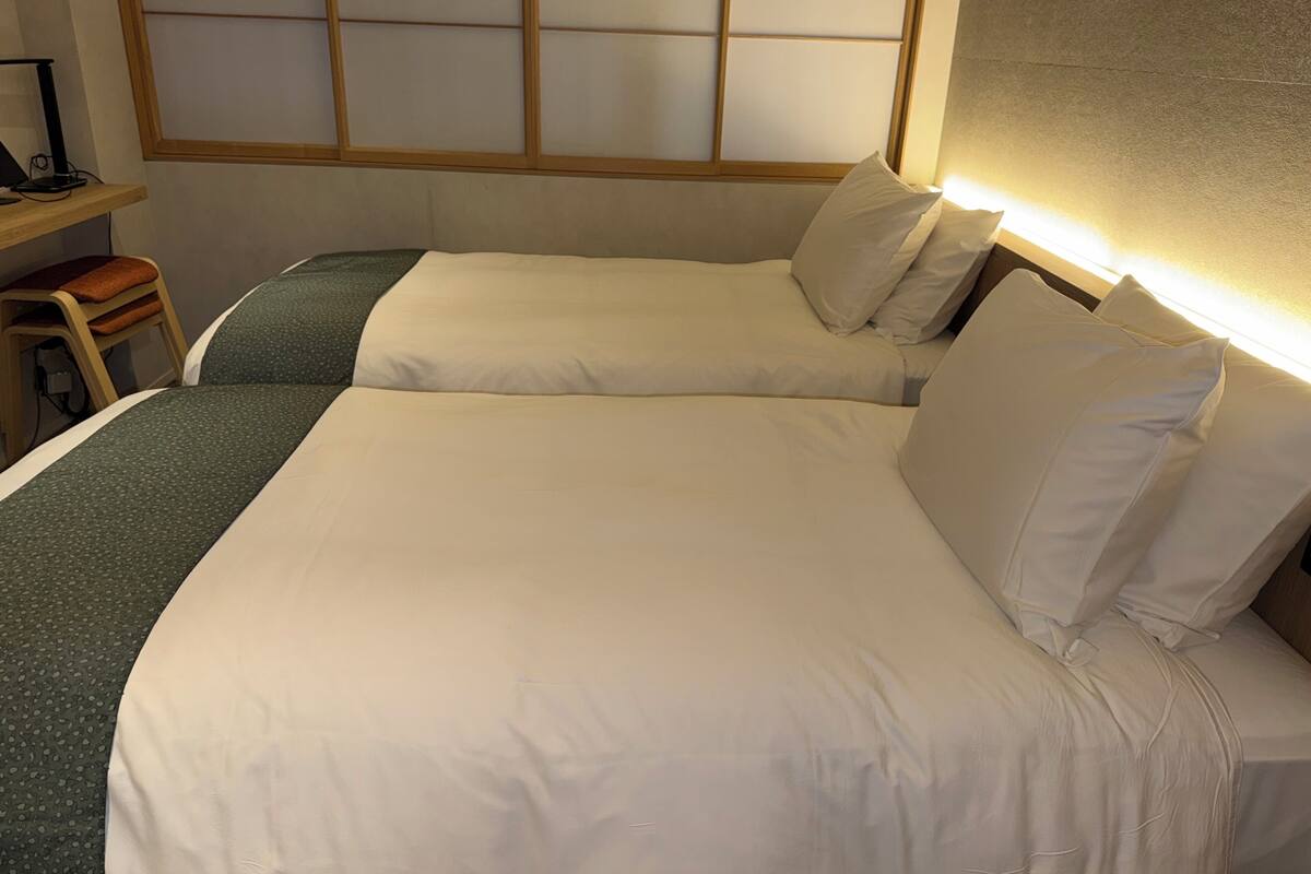 Een hotelkamer met twee bedden, een bureau en een stoel.