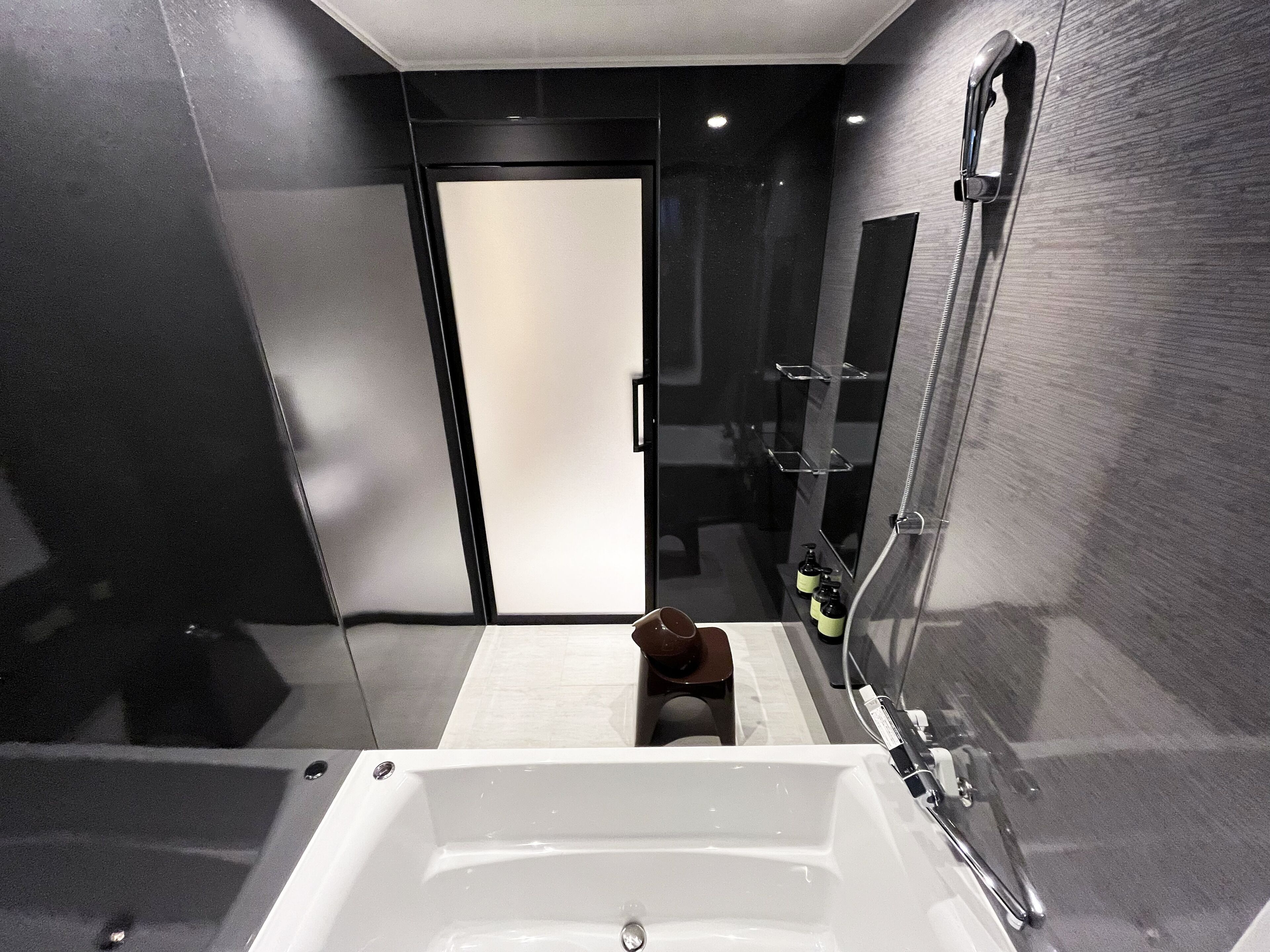 A modern bathroom with a large bathtub, a glass shower enclosure, and a door leading to another room.