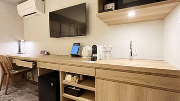 A modern kitchenette with a built-in microwave, a flat-screen TV, and a coffee machine.