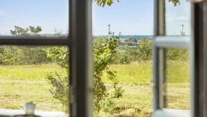 Uitzicht door een raam op een landelijk landschap, met velden en windturbines.