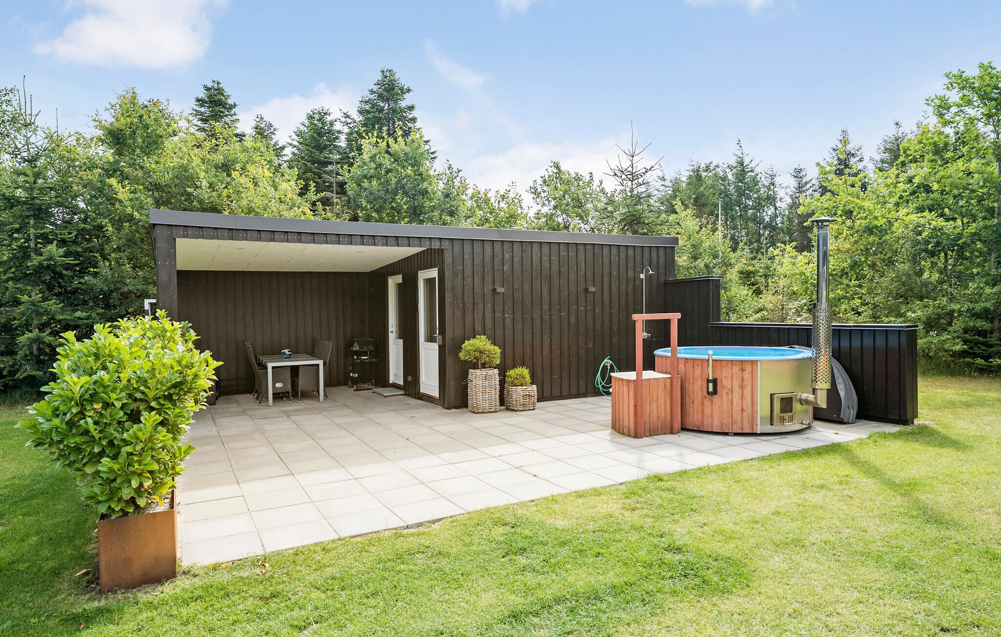 A covered patio area with a table and chairs, a hot tub, and a wooden deck.