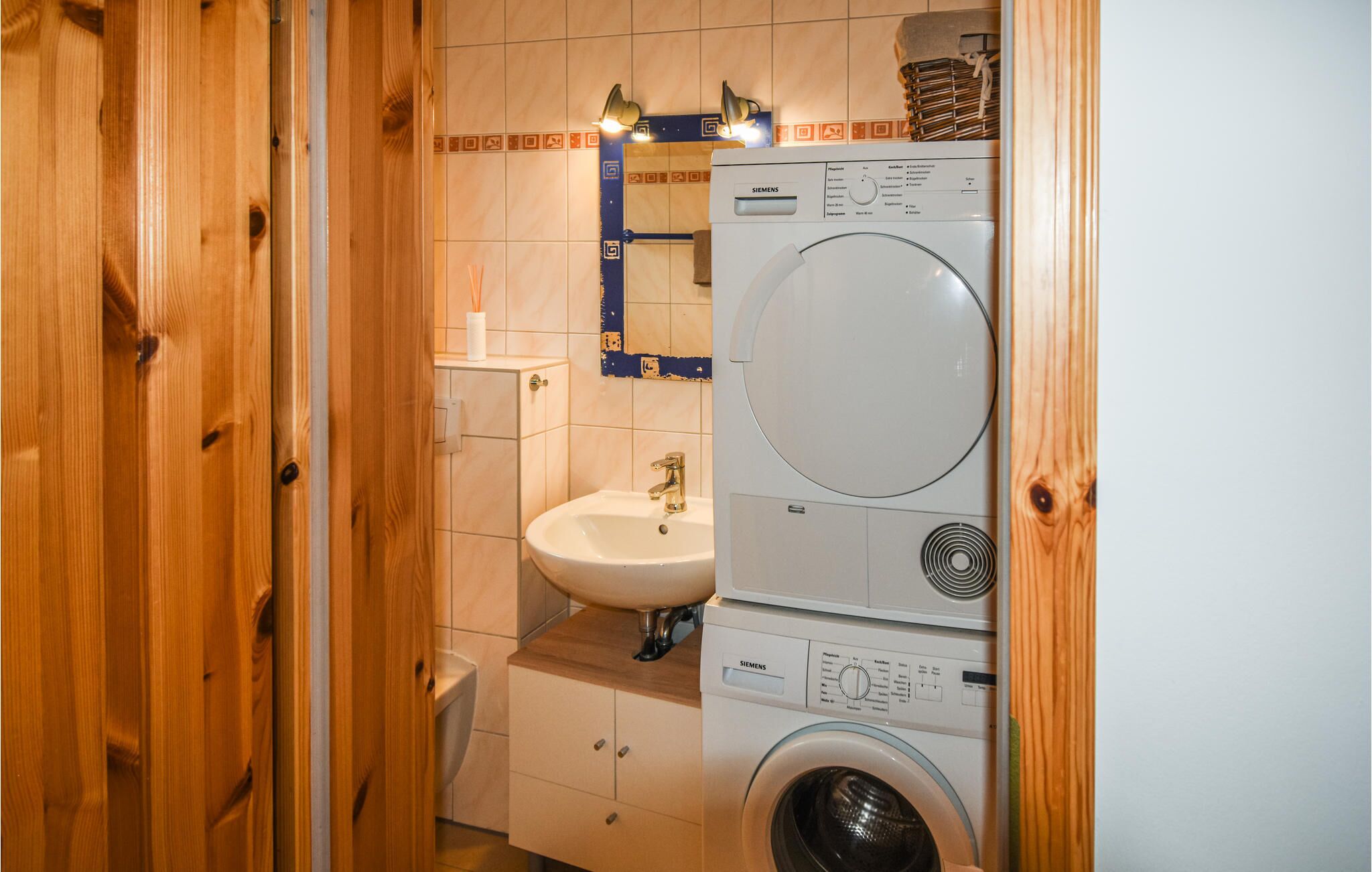 A compact laundry room with a washing machine, a sink, and a toilet.