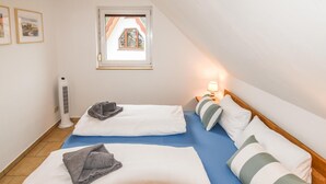 Ein Zimmer mit zwei Betten, einem Fenster mit Blick, einem Heizkörper und einer Nachttischlampe.