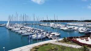 Un port de plaisance où sont amarrés de nombreux voiliers, un ciel dégagé et un espace aménagé avec des sièges.