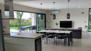 Une cuisine moderne avec un coin repas, une grande fenêtre et un téléviseur à écran plat.