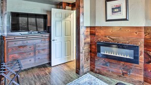 A room with a wooden wall, a fireplace, a dresser, and a door. - Peace & Quiet on Alpaca Farm! Paola Studio (Paola)