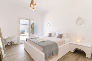 A modern bedroom with a large bed, bedside table, and a view of the outdoors.