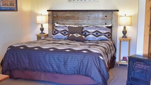 A bedroom with a bed, two bedside tables, a wall sign, and a lamp.
