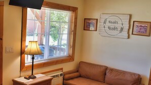 A cozy room with a window, a sofa, a lamp, a heater, and wall decorations.