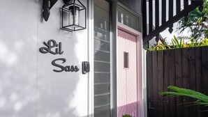 A building with a white exterior, a pink door, and a wooden fence. - Lil Sass on Sassifras - stylish one bedroom apartment, walk to beach (Mudjimba)