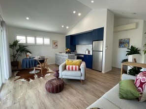 Un salon moderne comprenant un canapé, une table à manger et un coin cuisine avec des meubles bleus et un réfrigérateur.