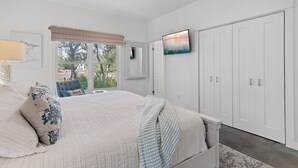 Een slaapkamer met een groot bed, een plafondventilator, een televisie en een kledingkast.