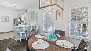 Een moderne keuken met een koelkast, spoelbak en een eethoek met een houten tafel en stoelen.