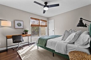 Un dormitorio con cama, escritorio, silla y ventilador de techo.