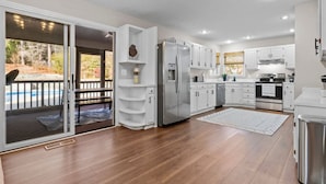 A modern kitchen with white cabinets, stainless steel appliances, and a wooden floor. - Southern Pines Getaway w/Hot Tub, Fire Pit & Pool (Southern Pines)