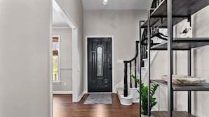 A modern hallway with a black door, wooden flooring, and a staircase with black railings. - Southern Pines Getaway w/Hot Tub, Fire Pit & Pool (Southern Pines)