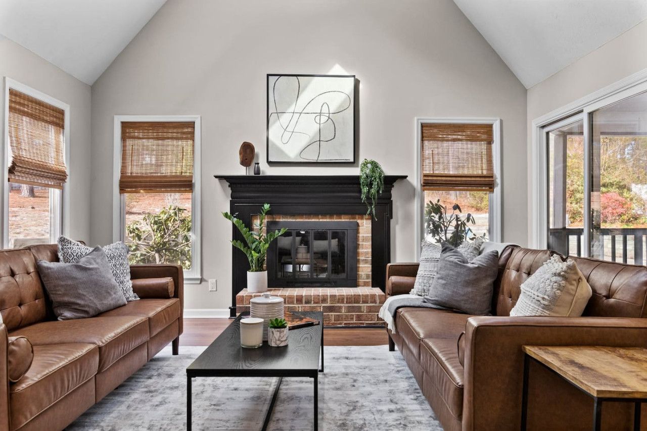 A living room with two leather sofas, a fireplace, and a large abstract painting.