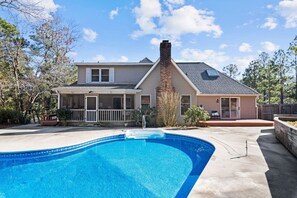 A two-story house with a swimming pool in the foreground.
